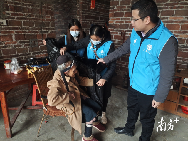 連南瑤族自治縣香坪鎮(zhèn)社工站為困難高齡老人送去御寒棉衣，并幫老人穿上棉衣。